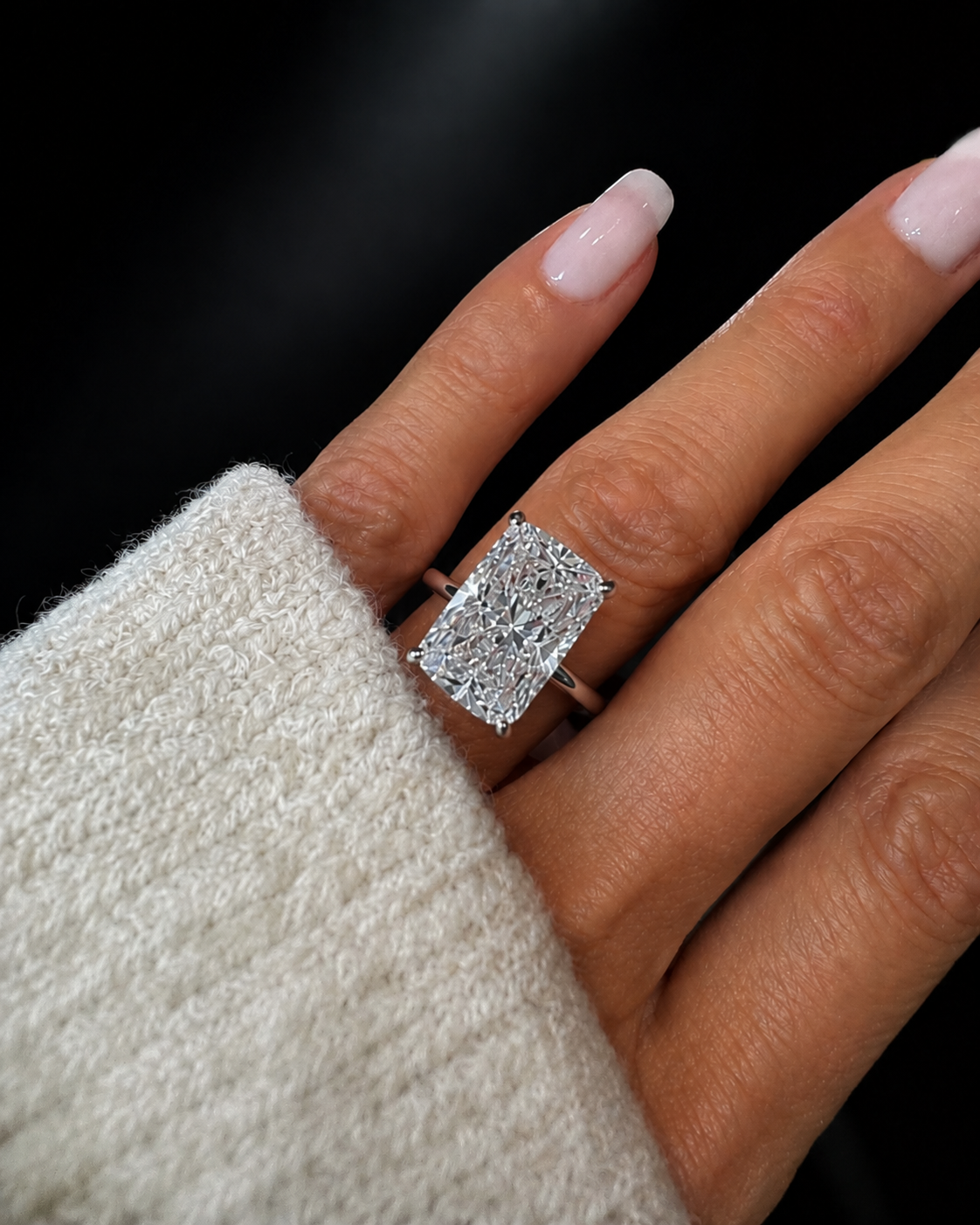 Hand wearing a 10 carat large diamond ring with a dark background