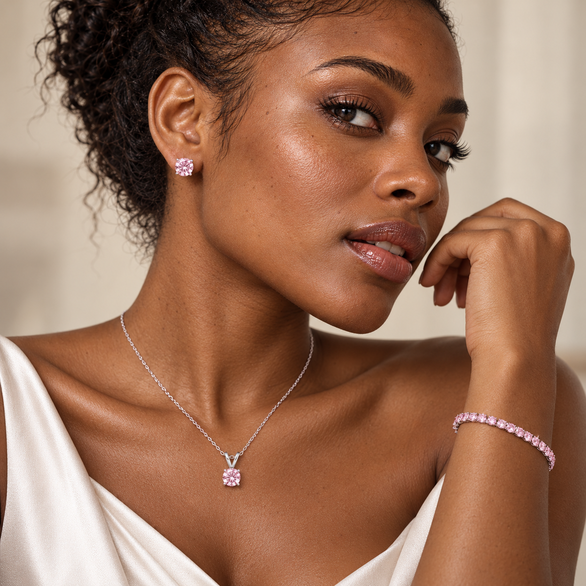 Model wearing a pink lab grown diamond jewelry set with stud earrings, solitaire pendant necklace and tennis bracelet in 14K white gold.