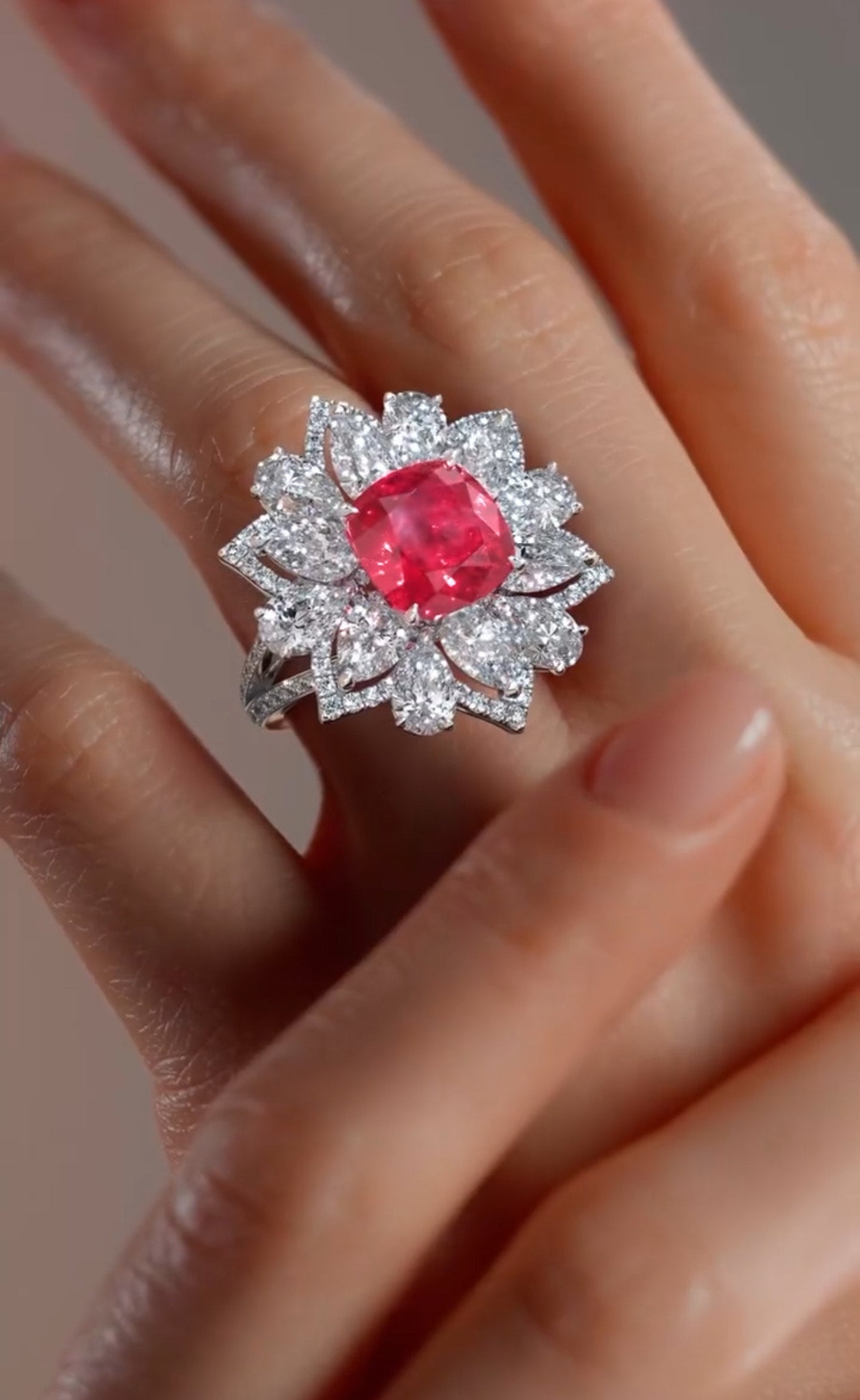 Red lab diamond floral ring surrounded by clear lab diamonds worn on a woman's hand