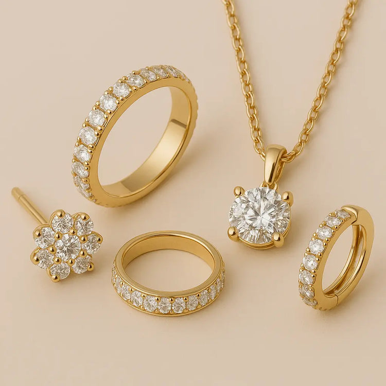 Elegant flat lay of essential fine jewelry pieces in 14K gold featuring lab diamond studs, a sleek gold band, a solitaire pendant, and small hoop earrings on a beige background.