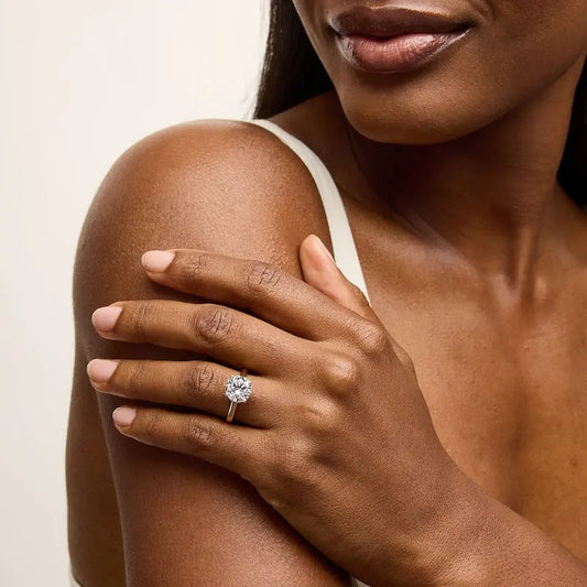 Gold ring with a large diamond on a white background on a model