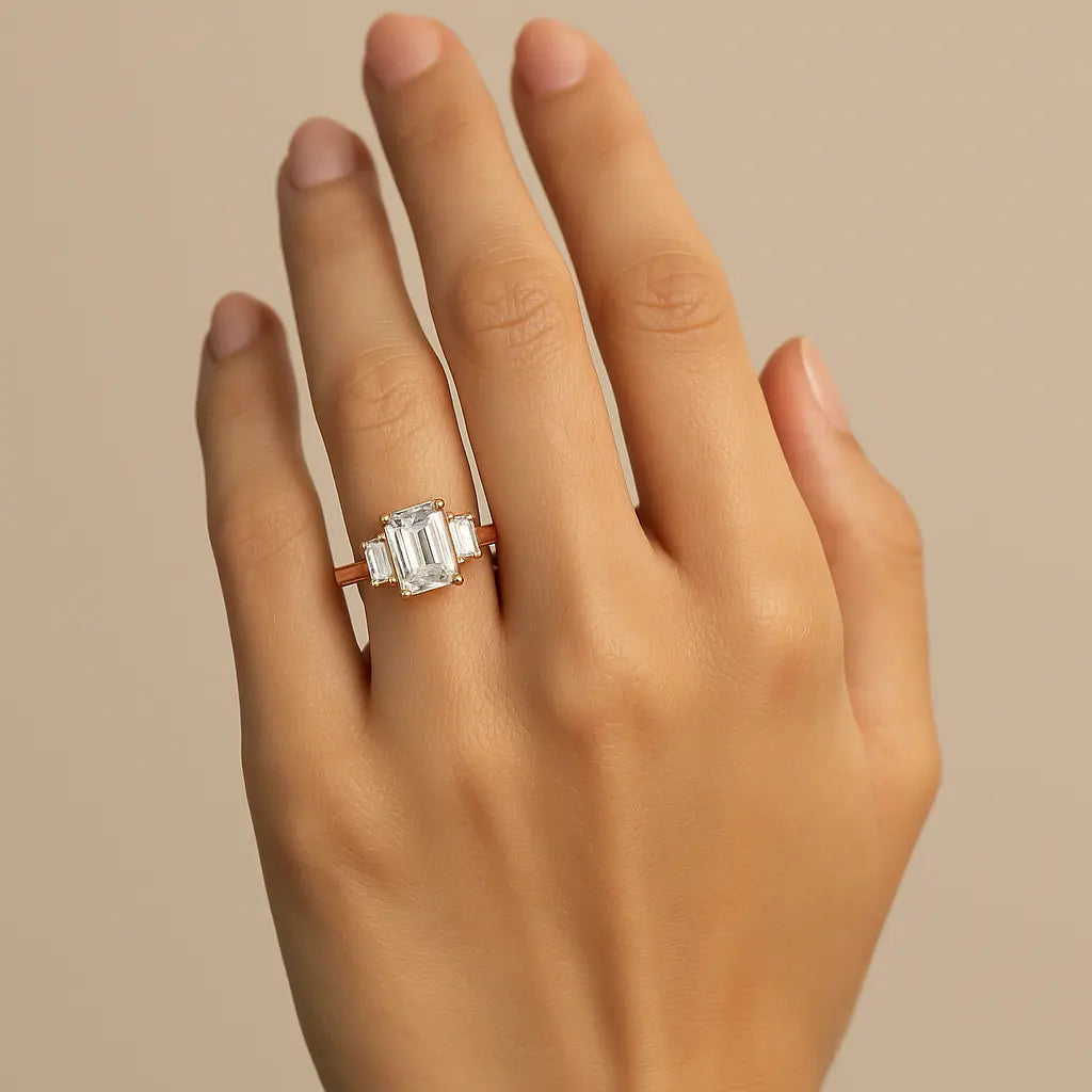 Rose gold ring with emerald cut diamond on a white background on hand