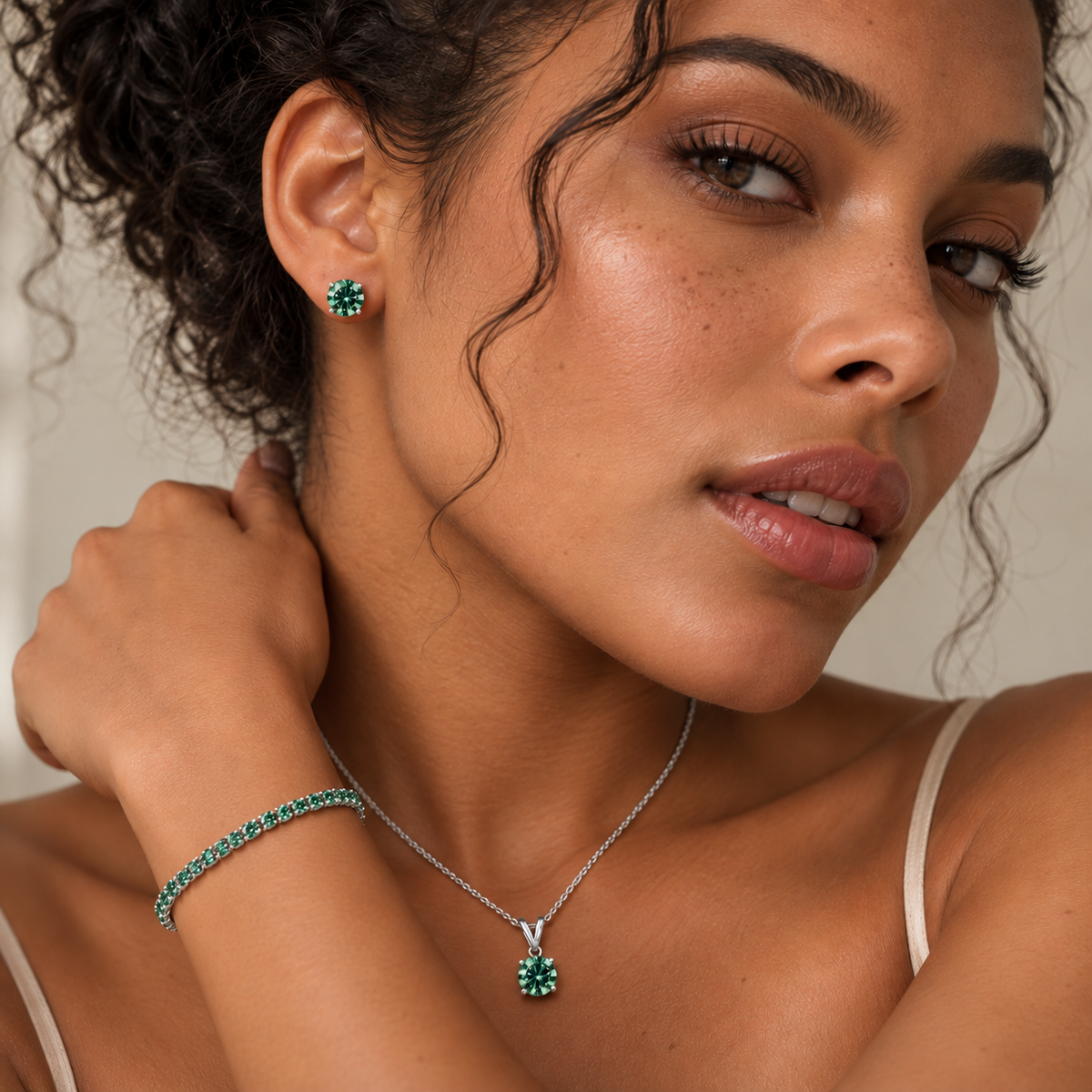 Model wearing a green lab grown diamond jewelry set with stud earrings, solitaire pendant necklace and tennis bracelet in 14K white gold.