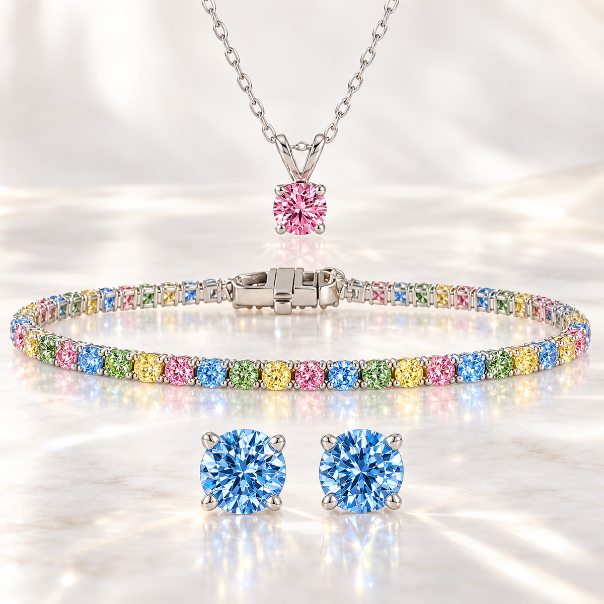 Rainbow lab grown diamond jewelry set with a multicolor tennis bracelet, pink solitaire pendant and blue stud earrings in 14K white gold.