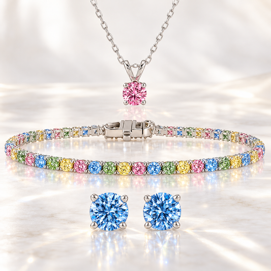 Rainbow lab grown diamond jewelry set with a multicolor tennis bracelet, pink solitaire pendant and blue stud earrings in 14K white gold.