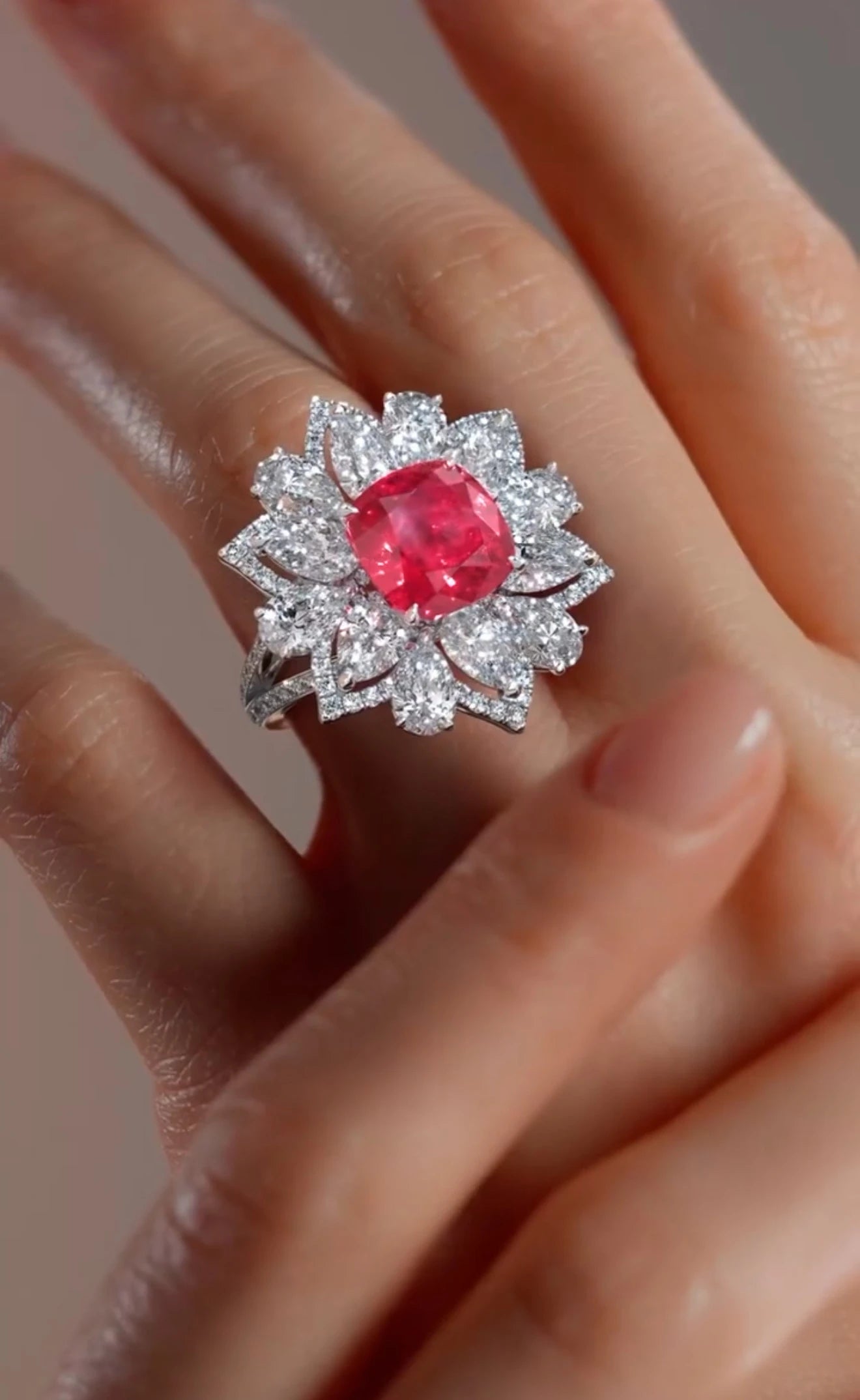 Red lab diamond floral ring surrounded by clear lab diamonds worn on a woman's hand